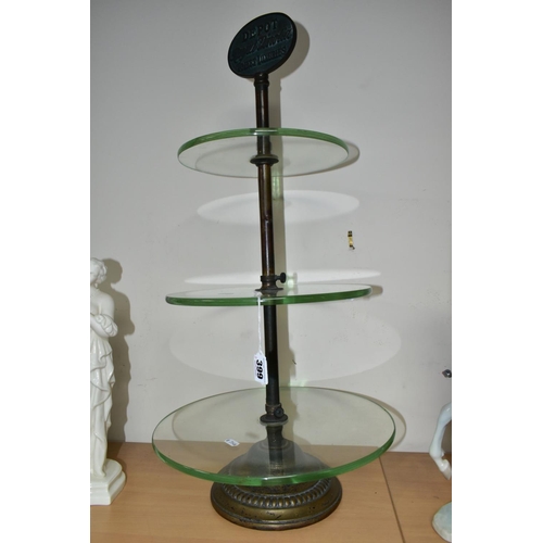 399 - AN EARLY 20TH CENTURY THREE TIER GLASS ADVERTISING DISPLAY STAND, the iron and worn brassed stand wi... 