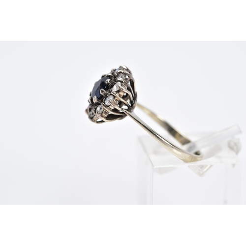 53 - A WHITE METAL SAPPHIRE AND DIAMOND CLUSTER RING, designed with a central circular cut blue sapphire ... 