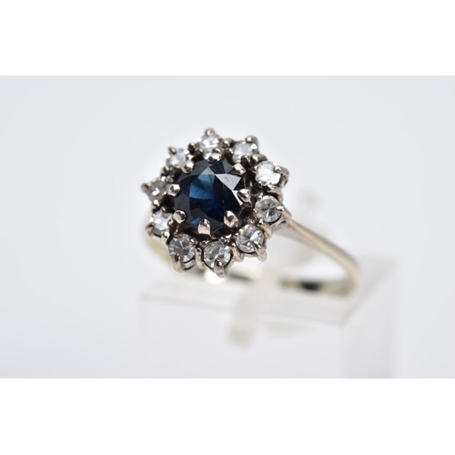 53 - A WHITE METAL SAPPHIRE AND DIAMOND CLUSTER RING, designed with a central circular cut blue sapphire ... 