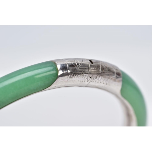 36 - A WHITE METAL AND JADE HINGED BANGLE, jade bangle lined with a decorative white metal lining, fitted... 