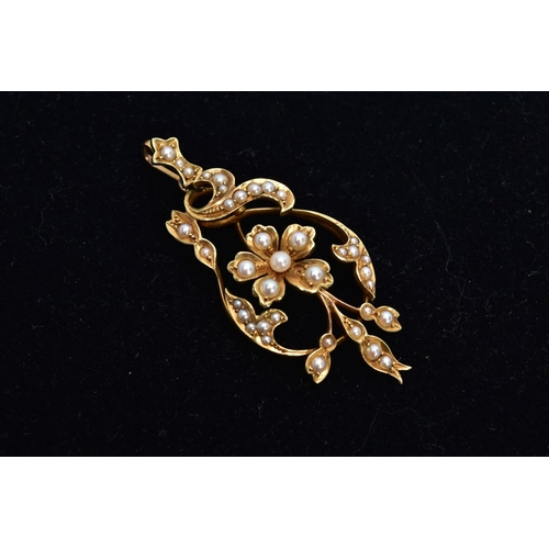 104 - A YELLOW METAL SEED PEARL PENDANT, of an openwork design, featuring a central flower set with a seed... 