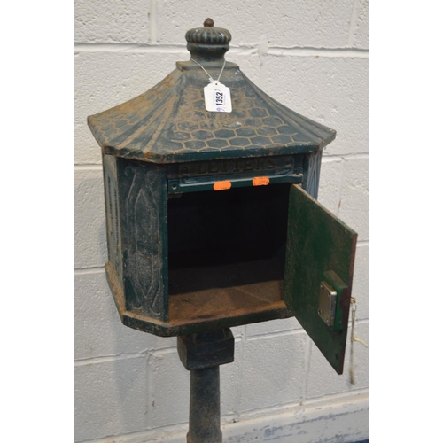 1352 - A GREEN PAINTED CAST IRON LETTER BOX on a stand (one bolt missing between base and pillar) (key)