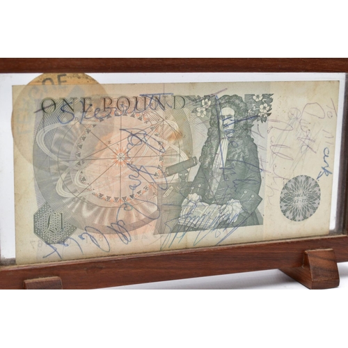 29 - A FRAMED BANK OF ENGLAND 'ONE POUND NOTE', within a wooden frame, raised on two block feet, the note... 