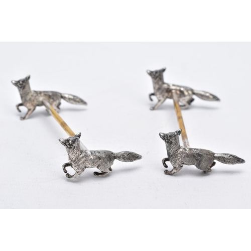 32 - A PAIR OF WHITE METAL KNIFE RESTS, each rest modelled with two foxes to each end with a worn gilt re... 