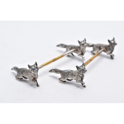 32 - A PAIR OF WHITE METAL KNIFE RESTS, each rest modelled with two foxes to each end with a worn gilt re... 