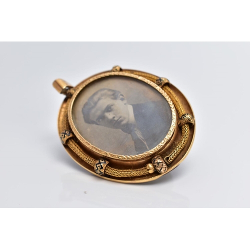 38 - A YELLOW METAL PORTRAIT PENDANT, of an oval form, holding a photo of a gentleman, within a textured ... 