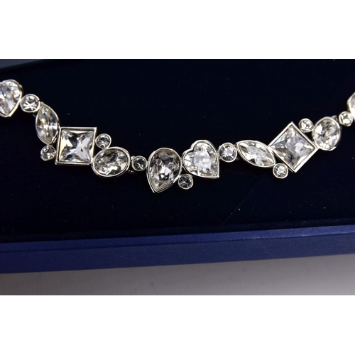 47 - A WHITE METAL SWAROVSKI CRYSTAL NECKLACE, of an articulated design set with various cut colourless c... 