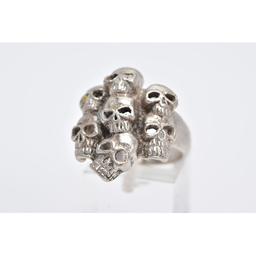 108 - A GENTS WHITE METAL SKULL RING, designed with seven pierced skulls, stamped '925', ring size O, appr... 