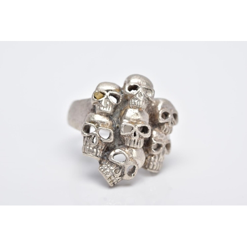 108 - A GENTS WHITE METAL SKULL RING, designed with seven pierced skulls, stamped '925', ring size O, appr... 