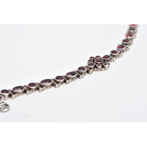 111 - A WHITE METAL, GARNET SET LINE BRACELET, articulated bracelet, designed with a central cluster of ro... 