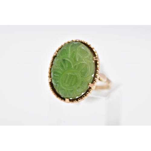 13 - A 9CT GOLD, CARVED NEPHRITE CAMEO RING, of an oval form with a carved floral design, beaded surround... 