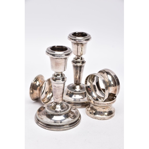 90 - A PAIR OF SILVER DWARF CANDLESTICKS AND THREE NAPKIN RINGS, each candlestick has a round weighted ba... 