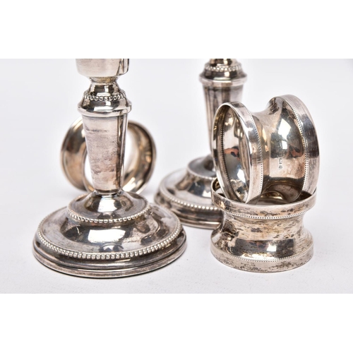 90 - A PAIR OF SILVER DWARF CANDLESTICKS AND THREE NAPKIN RINGS, each candlestick has a round weighted ba... 