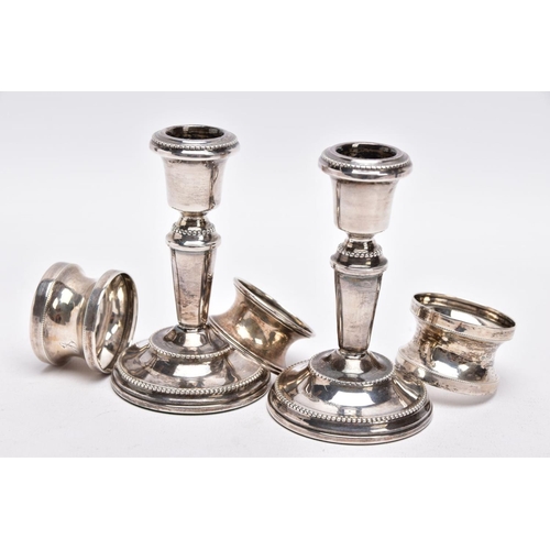 90 - A PAIR OF SILVER DWARF CANDLESTICKS AND THREE NAPKIN RINGS, each candlestick has a round weighted ba... 