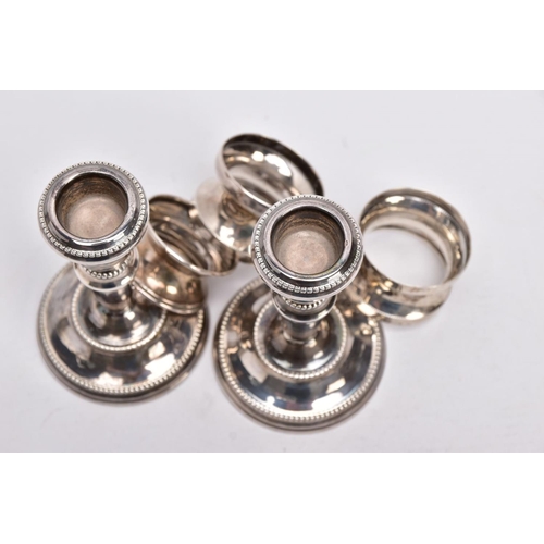 90 - A PAIR OF SILVER DWARF CANDLESTICKS AND THREE NAPKIN RINGS, each candlestick has a round weighted ba... 