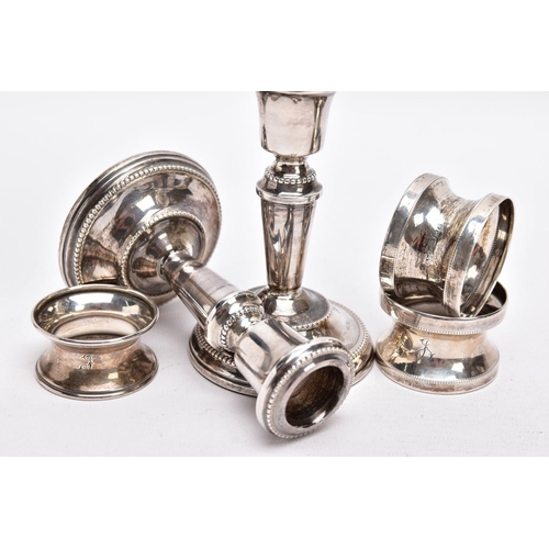 90 - A PAIR OF SILVER DWARF CANDLESTICKS AND THREE NAPKIN RINGS, each candlestick has a round weighted ba... 
