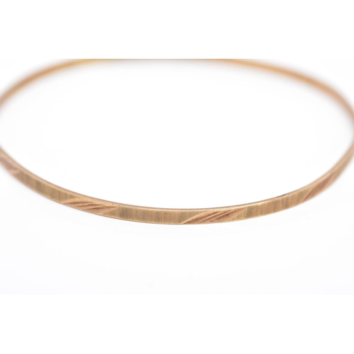 118 - A 9CT GOLD BANGLE, thin bangle with a textured and foliate engraved design, hallmarked 9ct gold Lond... 