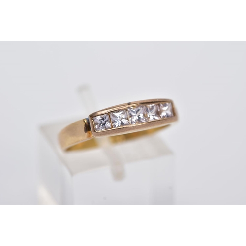 12 - A YELLOW METAL HALF HOOP RING, designed with a row of graduated square cut colourless stones, assess... 