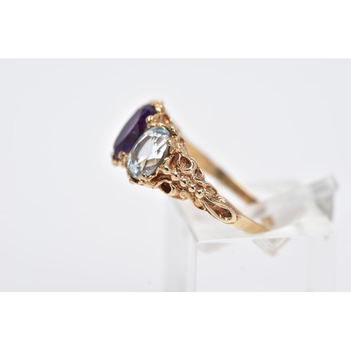 132 - A 9CT GOLD THREE STONE RING, centring on an oval cut amethyst, flanked with two oval cut aquamarines... 