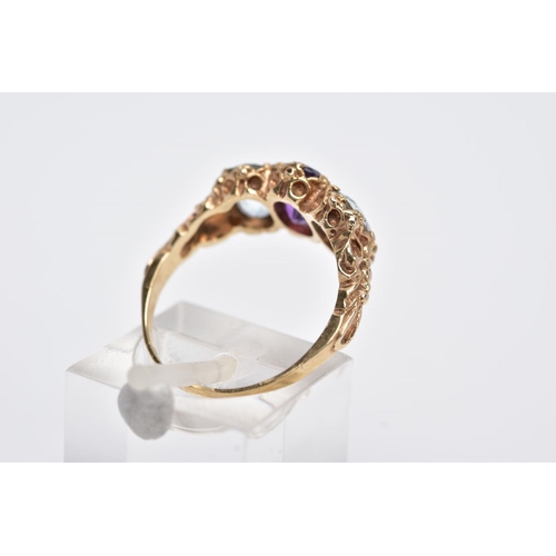 132 - A 9CT GOLD THREE STONE RING, centring on an oval cut amethyst, flanked with two oval cut aquamarines... 