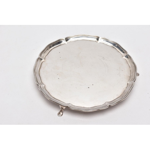 216 - A GEORGE V SILVER SALVER, circular form with a beaded wavy rim, raised on three cabriolet legs, hall... 