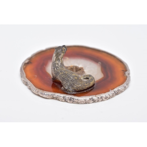 24 - A WHITE METAL OTTER ON AN AGATE AND SILVER MOUNTED BASE, textured figure of an otter fixed onto a ci... 