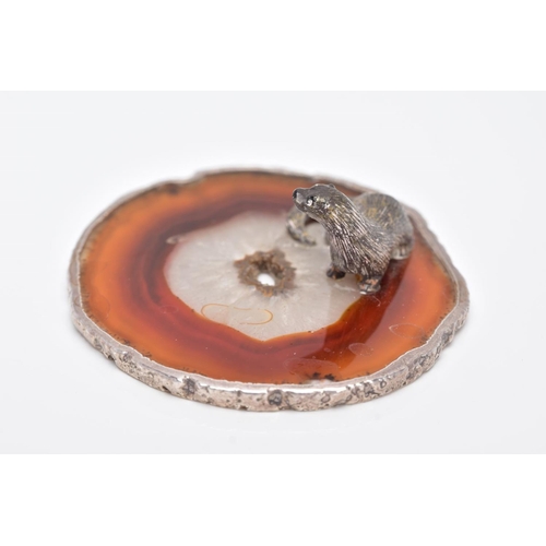 24 - A WHITE METAL OTTER ON AN AGATE AND SILVER MOUNTED BASE, textured figure of an otter fixed onto a ci... 