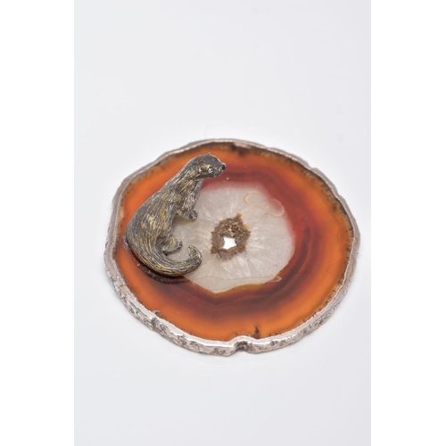 24 - A WHITE METAL OTTER ON AN AGATE AND SILVER MOUNTED BASE, textured figure of an otter fixed onto a ci... 