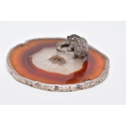 24 - A WHITE METAL OTTER ON AN AGATE AND SILVER MOUNTED BASE, textured figure of an otter fixed onto a ci... 