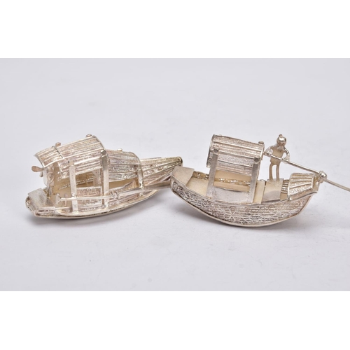 244 - TWO MODERN ORIENTAL, WHITE METAL FILIGREE BOAT ORNAMENTS, one with a standing figure with paddle, ap... 