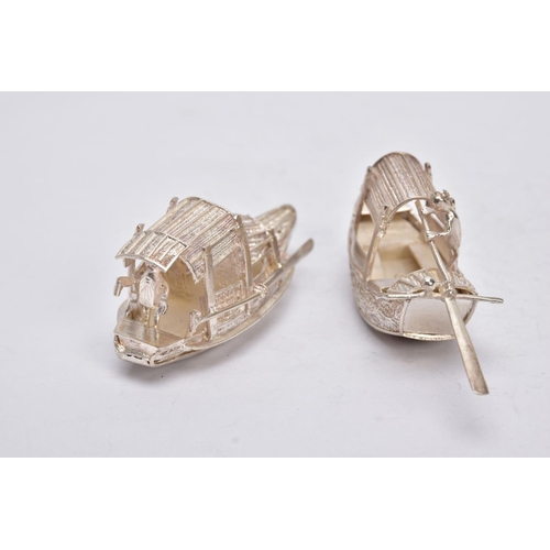 244 - TWO MODERN ORIENTAL, WHITE METAL FILIGREE BOAT ORNAMENTS, one with a standing figure with paddle, ap... 