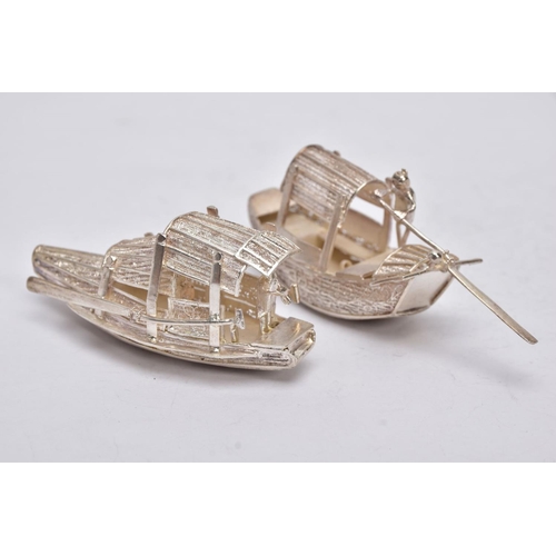 244 - TWO MODERN ORIENTAL, WHITE METAL FILIGREE BOAT ORNAMENTS, one with a standing figure with paddle, ap... 