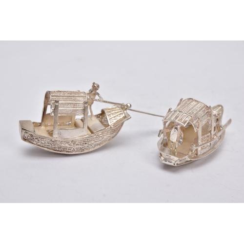 244 - TWO MODERN ORIENTAL, WHITE METAL FILIGREE BOAT ORNAMENTS, one with a standing figure with paddle, ap... 