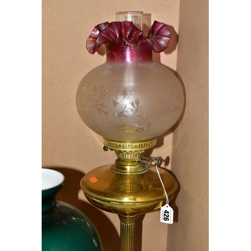 426 - A TWIN BURNER BRASS OIL LAMP HAVING ETCHED GLASS WITH CRANBERRY GLASS FRILLED SHADE, including chimn... 