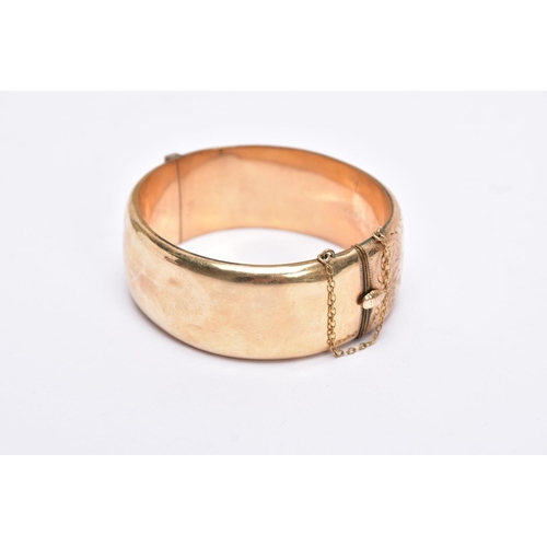 46 - A ROLLED GOLD WIDE BANGLE, hinged bangle with a half engraved foliate design, push pin clasp, fitted... 