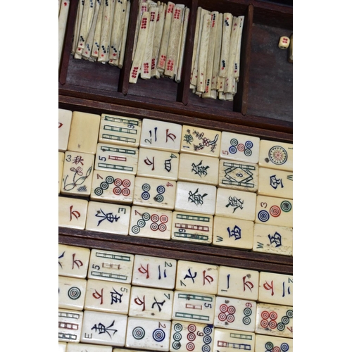 573 - A LATE 19TH/EARLY 20TH CENTURY MAH JONG SET, the bone and bamboo playing pieces housed in a relief c... 