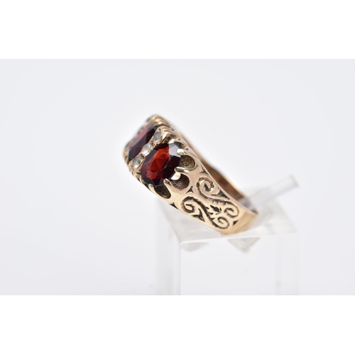 83 - A LATE 20TH CENTURY 9CT GOLD GARNET RING, designed with three oval cut garnets, interspaced with col... 