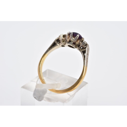 97 - A YELLOW METAL THREE STONE RING, design with a central circular cut purple stone, assessed as paste,... 