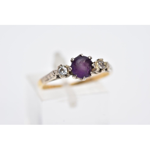 97 - A YELLOW METAL THREE STONE RING, design with a central circular cut purple stone, assessed as paste,... 