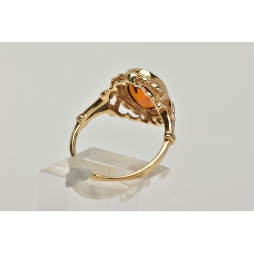 10 - A 9CT GOLD CITRINE AND DIAMOND RING, centring on a collet mounted oval cut citrine, openwork scallop... 