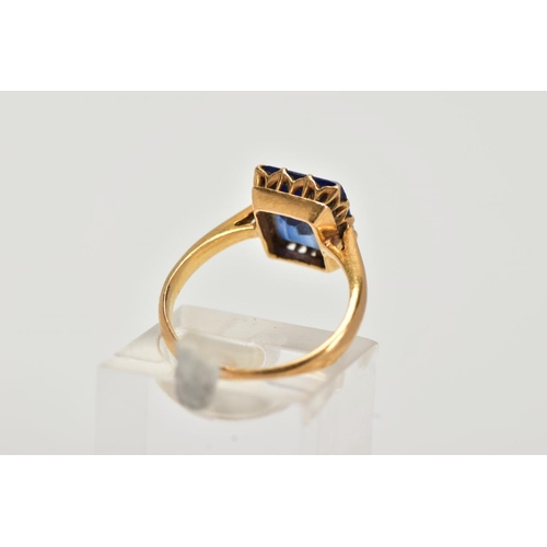 23 - A YELLOW METAL RING, designed with a claw set, rectangular cut synthetic blue sapphire, approximate ... 