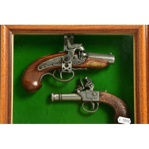 127 - A NEATLY FRAMED DISPLAY CASE containing a white metal replica of a percussion American derringer and... 