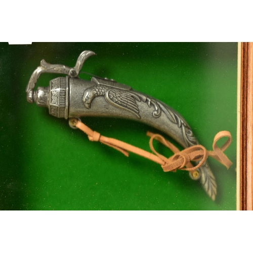 128 - A NEATLY FRAMED DISPLAY CASE containing a cast metal replica of a three barrel flintlock pistol fitt... 