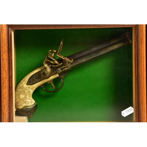 128 - A NEATLY FRAMED DISPLAY CASE containing a cast metal replica of a three barrel flintlock pistol fitt... 