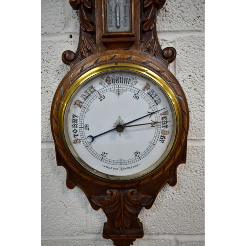 85A - A LATE VICTORIAN CARVED OAK ANEROID BAROMETER, with mercury thermometer and working blued indicator,... 