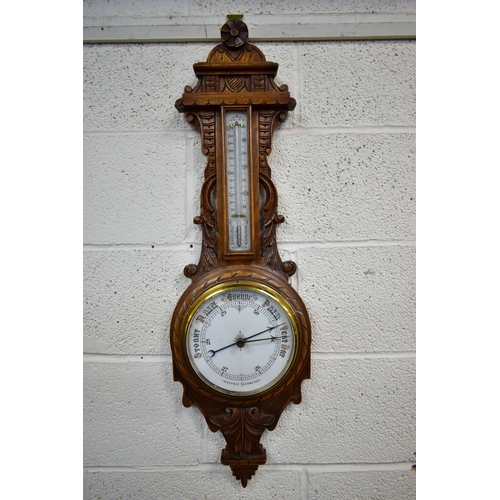 85A - A LATE VICTORIAN CARVED OAK ANEROID BAROMETER, with mercury thermometer and working blued indicator,... 