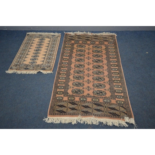 1387 - A WOOLEN PINK GROUND TEKKE RUG, 153cm x 93cm and a matching smaller rug (2)