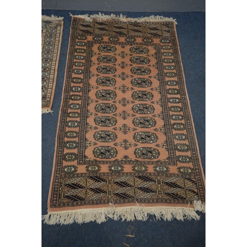 1387 - A WOOLEN PINK GROUND TEKKE RUG, 153cm x 93cm and a matching smaller rug (2)