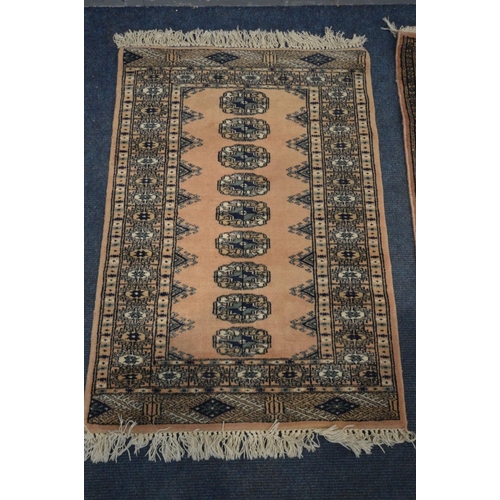 1387 - A WOOLEN PINK GROUND TEKKE RUG, 153cm x 93cm and a matching smaller rug (2)