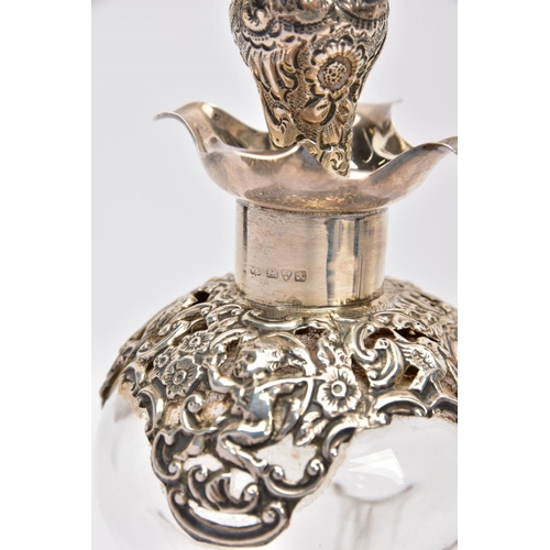 18 - AN EDWARDIAN GLASS AND SILVER DECANTER, the hour glass bottle with silver collar and stopper embosse... 